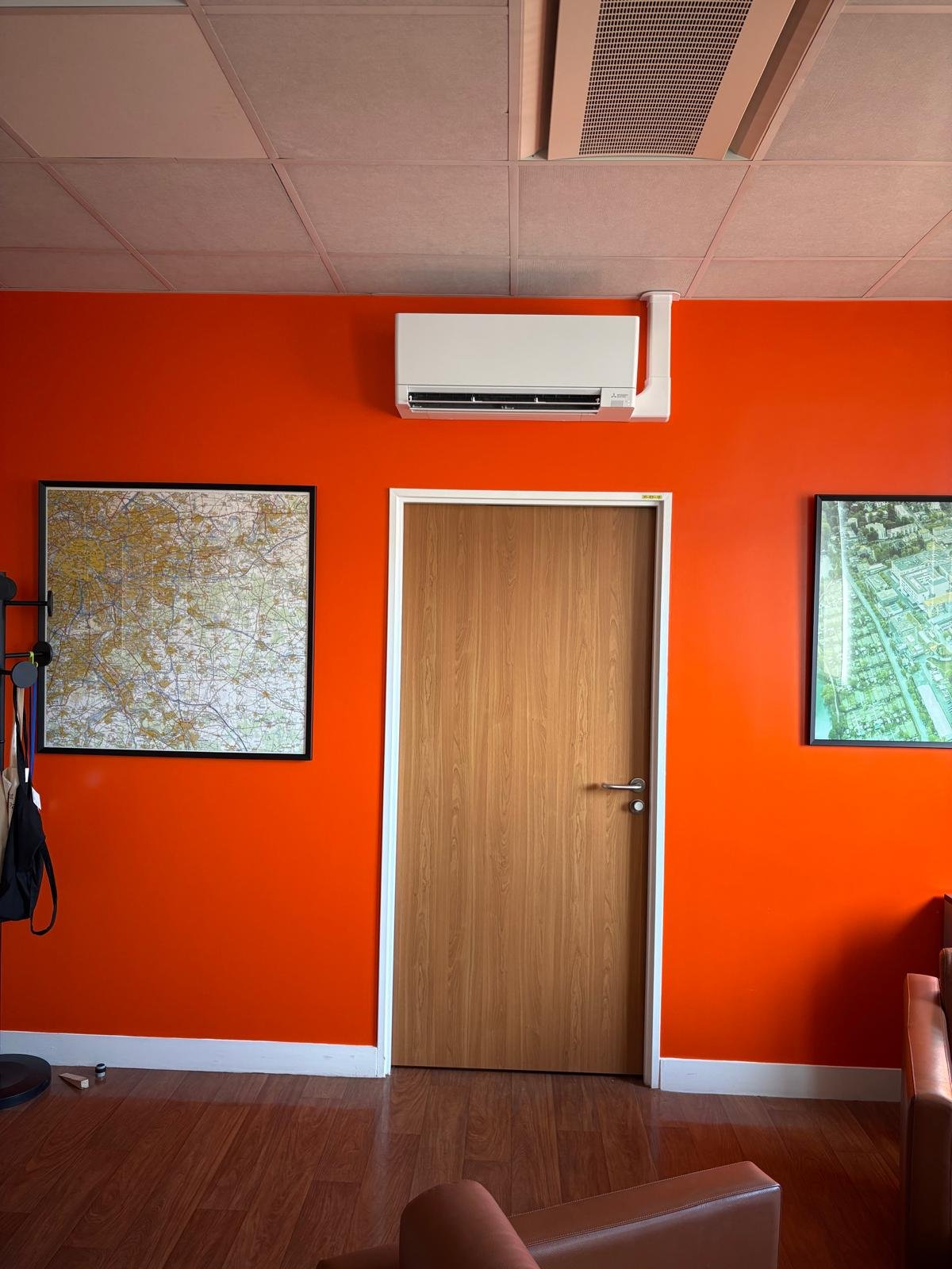 Vue de face du split mural Mitsubishi dans un bureau aux murs orange